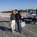 年轻的情侣带着行李离开私人飞机时亲吻